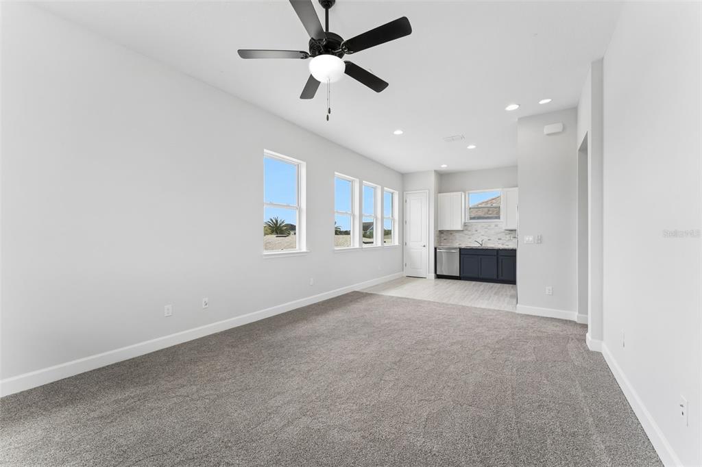 A carpeted living area opens to a kitchen with white upper and dark lower cabinets — 8033 NEMOURS PARKWAY, ORLANDO, FL