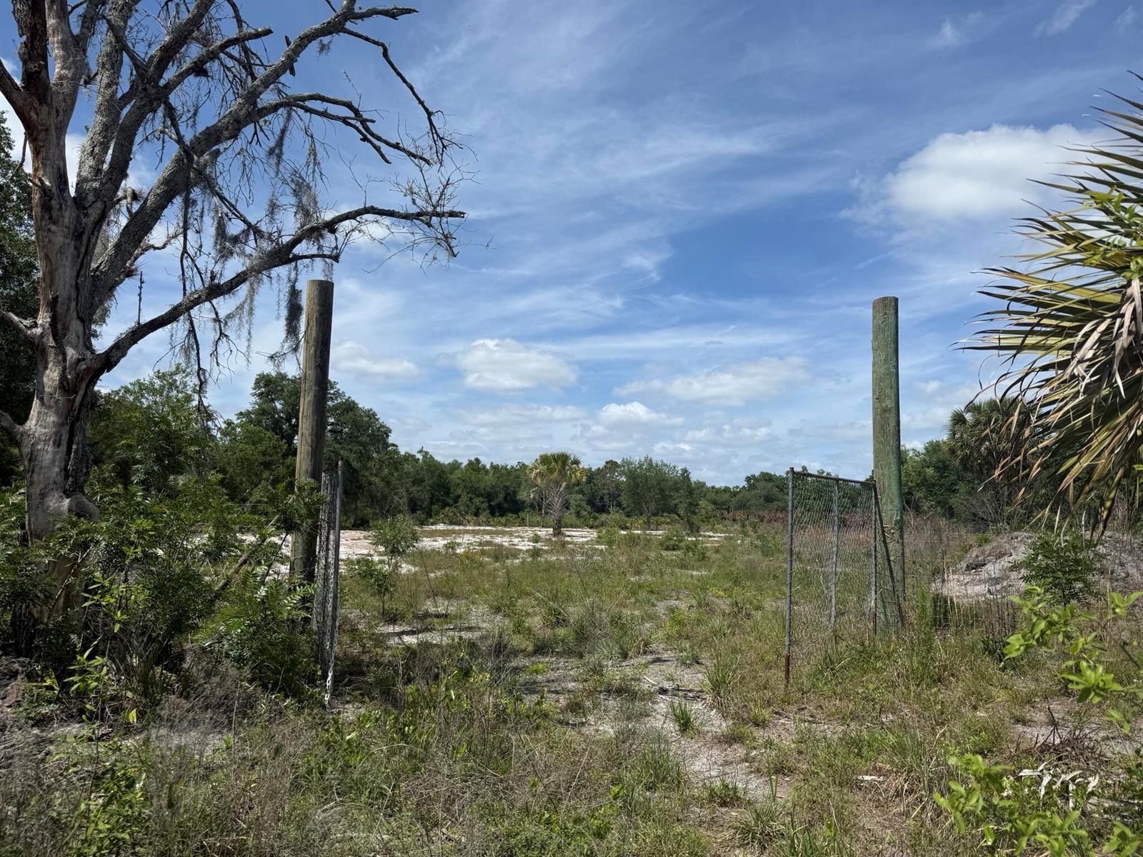 An open gate leads to a sandy, overgrown lot framed by two wooden posts — 18121 NW 256th Street, Okeechobee FL 34972, OKEECHOBEE, FL