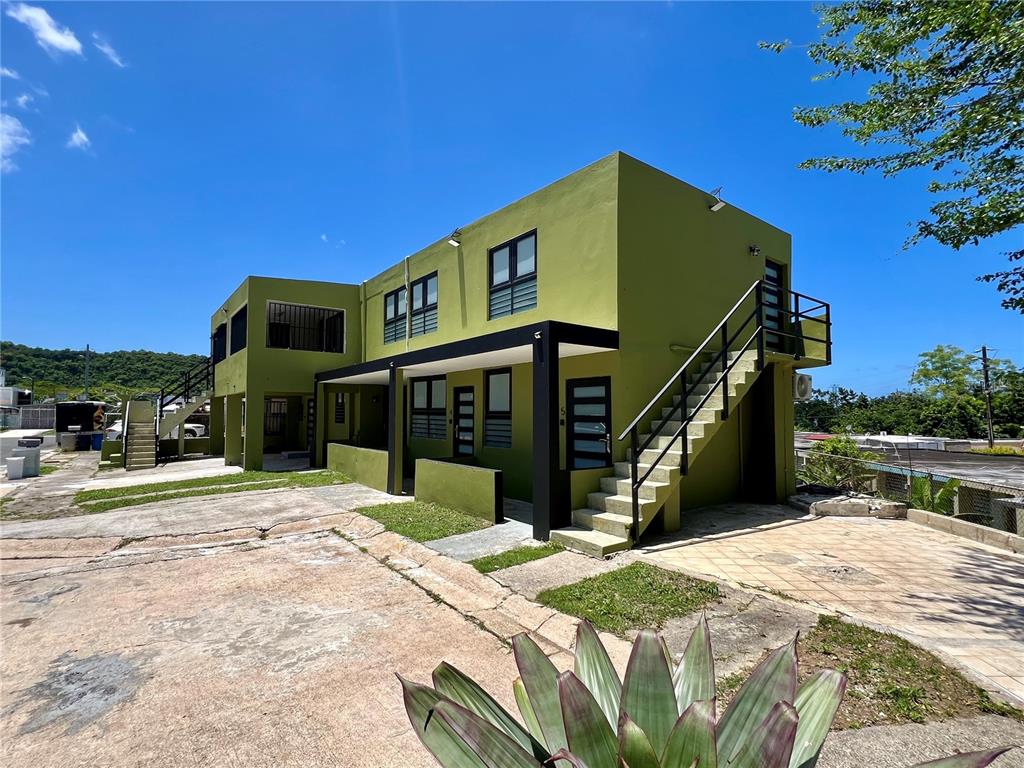 A two-story green apartment building features an exterior staircase and a paved parking area — 84  ST. URB SIERRA BAYAMON 98-1 APT. #7, BAYAMON, PR
