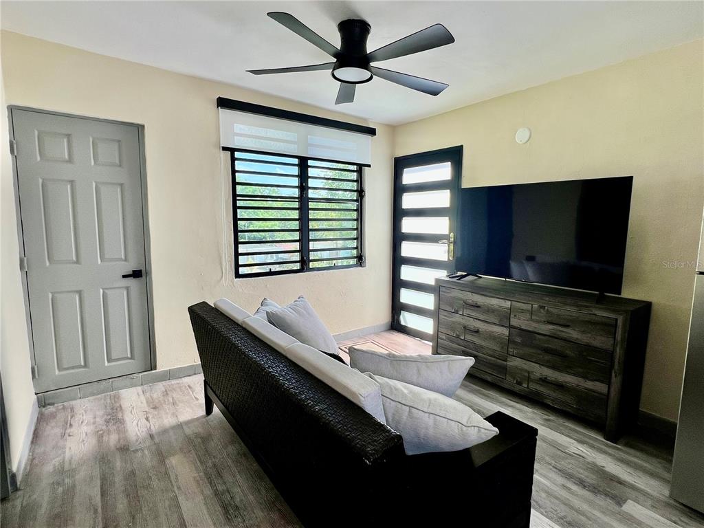 A living room features a dark sofa, a television on a dresser, and a ceiling fan — 84  ST. URB SIERRA BAYAMON 98-1 APT. #7, BAYAMON, PR