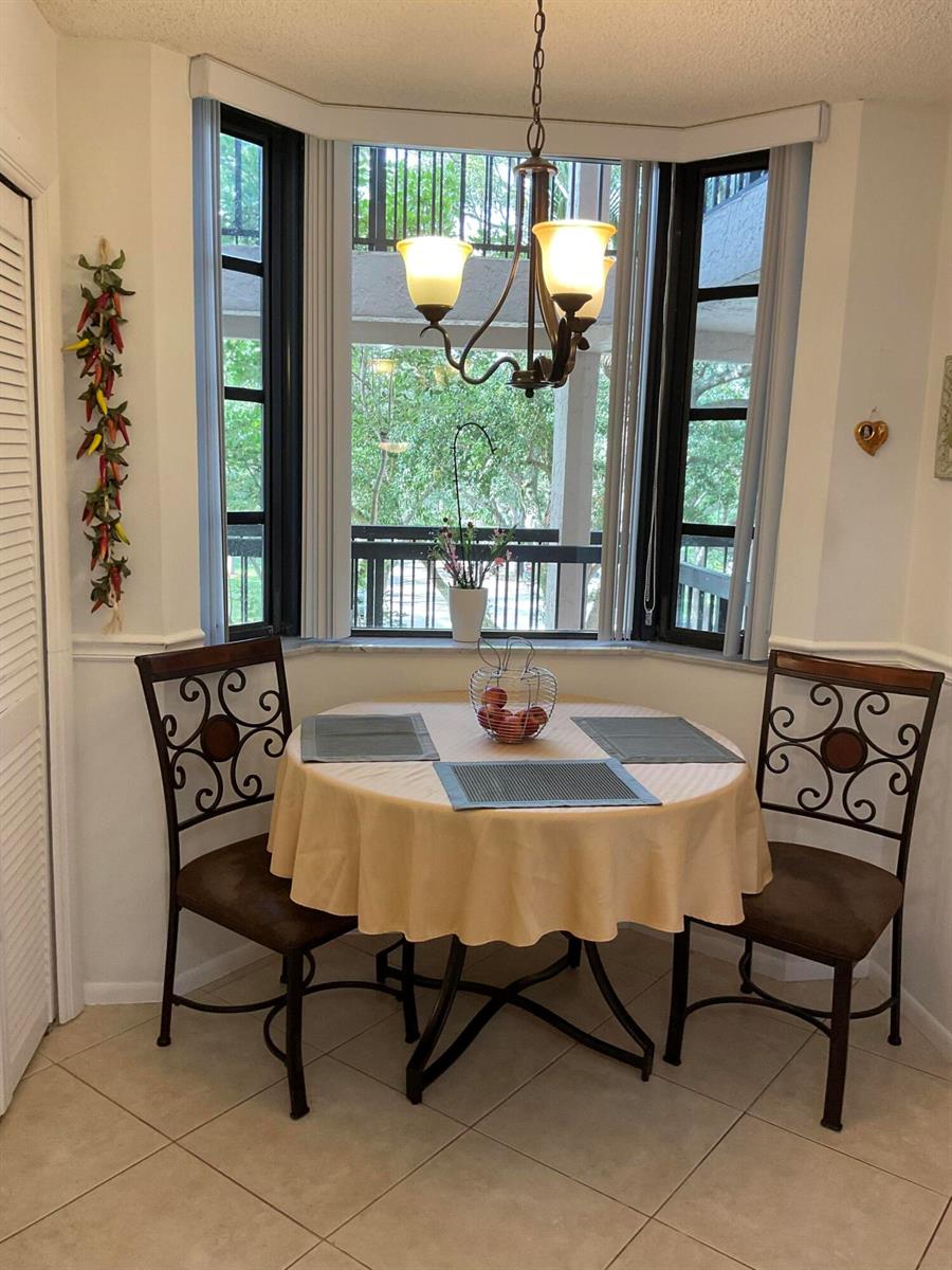 A dining nook features a round table, two metal chairs, and a large bay window — 6420 Boca Del Mar # 303, Boca Raton FL 33433, BOCA RATON, FL