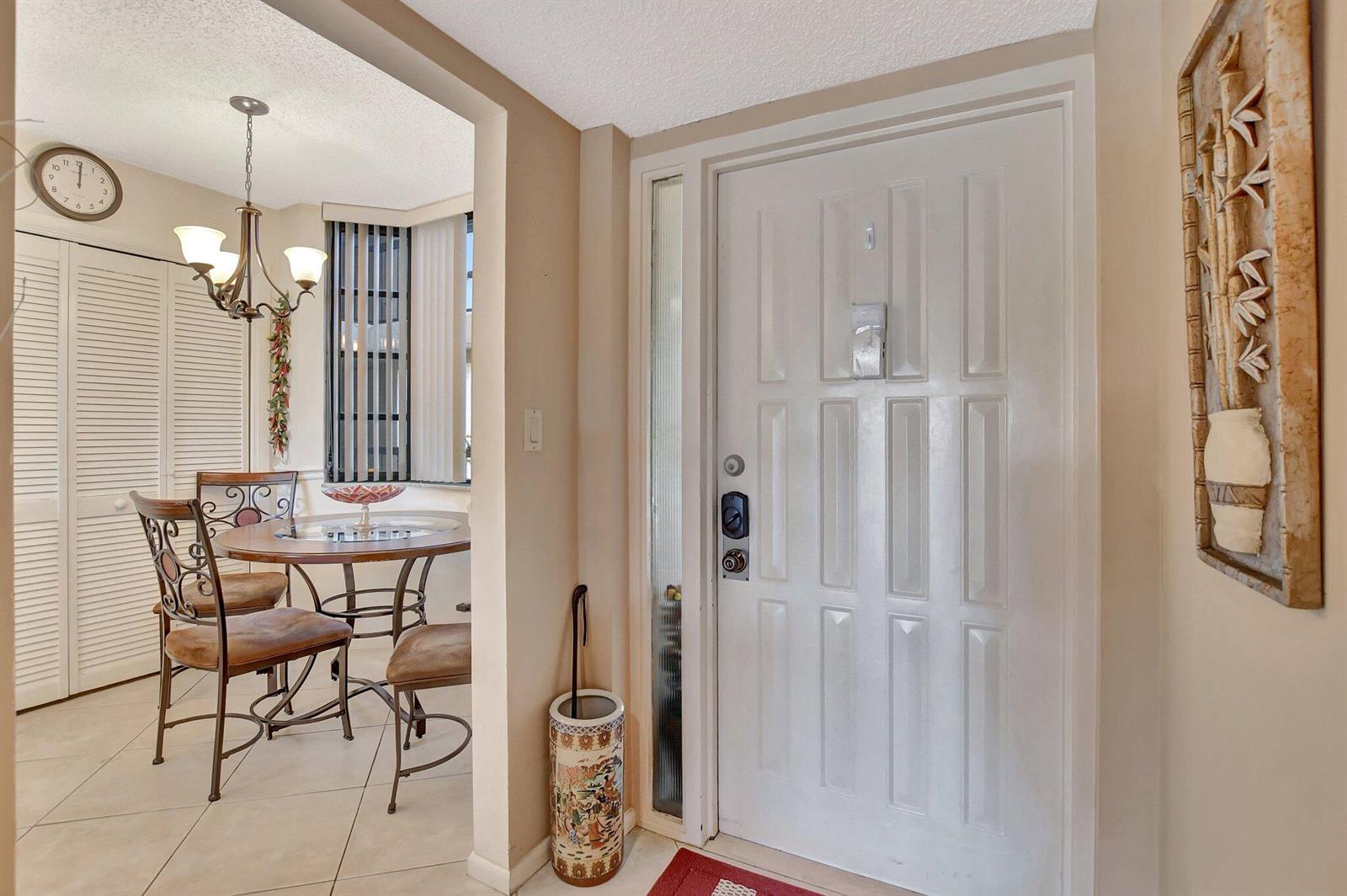 An entryway with a white door and an adjacent dining area featuring a round table — 6420 Boca Del Mar # 303, Boca Raton FL 33433, BOCA RATON, FL