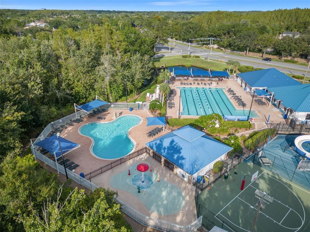 An aerial view shows a community pool complex with a lap pool, splash pad, and court — 28427 SUNVALE PLACE, WESLEY CHAPEL, FL