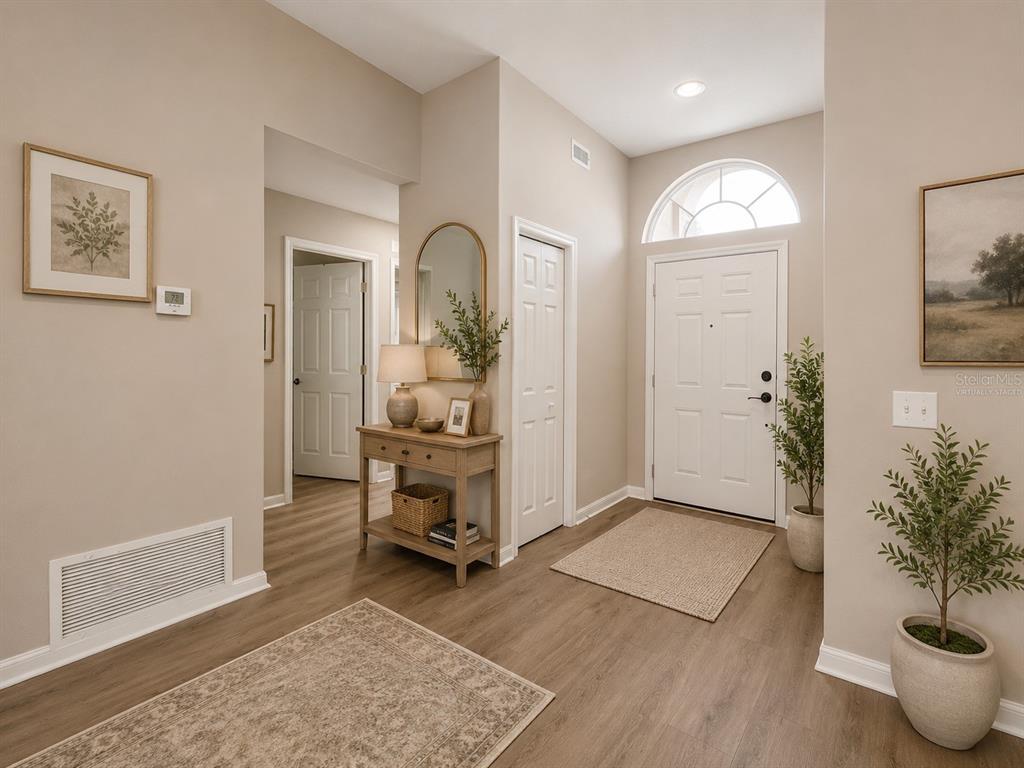A bright entryway features light wood-look flooring, a console table, and a white front door — 28427 SUNVALE PLACE, WESLEY CHAPEL, FL