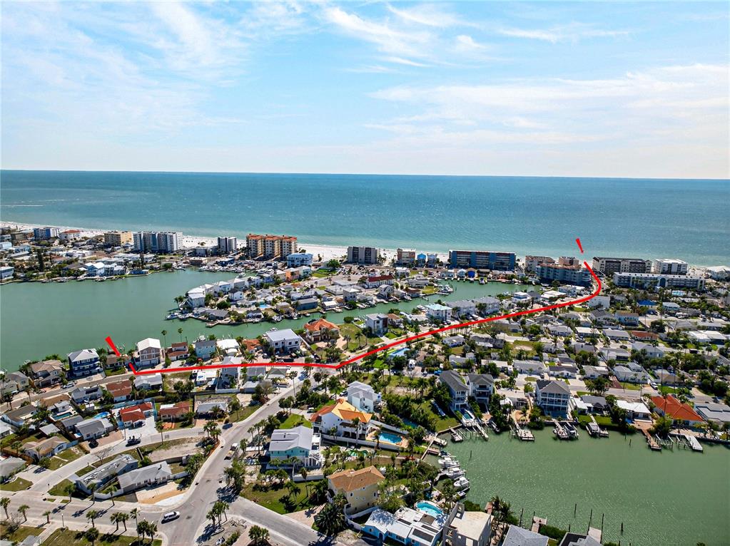 An aerial view shows a coastal neighborhood with a red line highlighting a specific path — 449 S BAYSHORE DRIVE, MADEIRA BEACH, FL