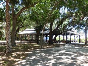 A large, open-air wooden pavilion with picnic tables sits under mature trees in a park — 17114 BARCREST LANE, PUNTA GORDA, FL