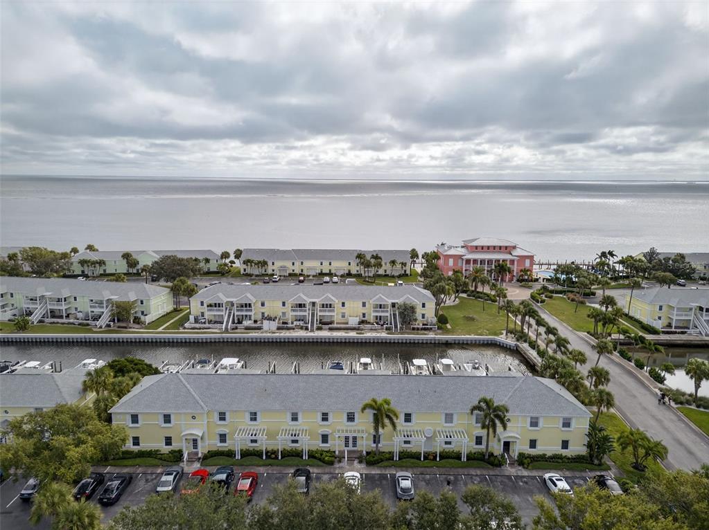 An aerial view shows yellow multi-story residential buildings, a canal with docked boats, and water — 4924 BEACH DRIVE SE UNIT F, ST PETERSBURG, FL