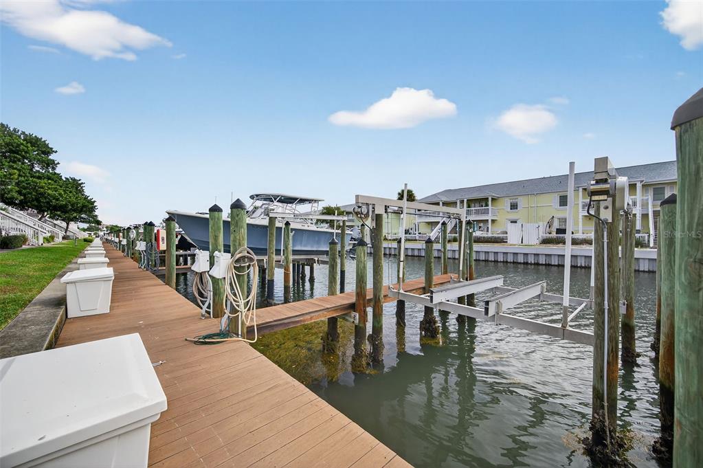 A wooden dock features boat lifts and storage bins along a canal beside residential buildings — 4924 BEACH DRIVE SE UNIT F, ST PETERSBURG, FL