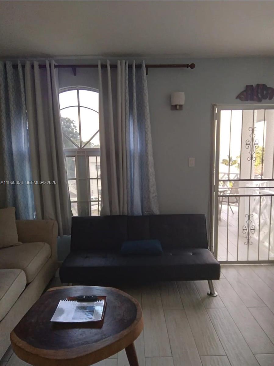 A living room features a dark futon, a wooden coffee table, and a balcony door — 00 Sky Castles, Ocho Rios # 00, FL, FL