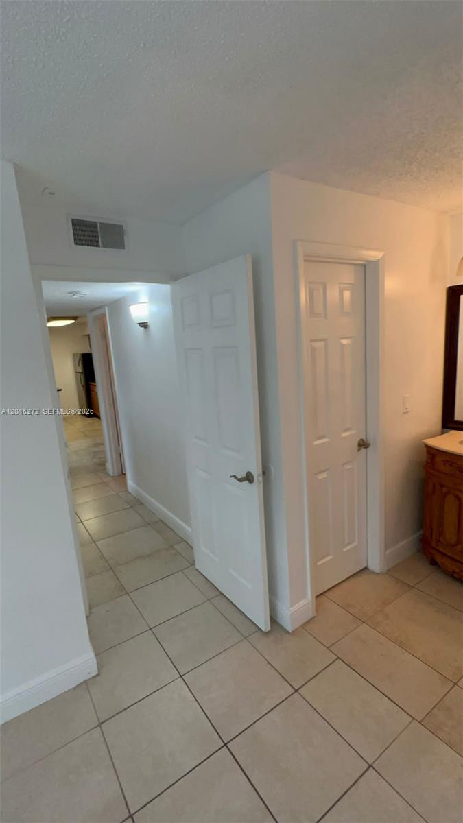 A hallway with tiled floors leads to a kitchen, with two closed white doors nearby — 1263 SW 46th Ave # 2104, Pompano Beach FL 33069, POMPANO BEACH, FL