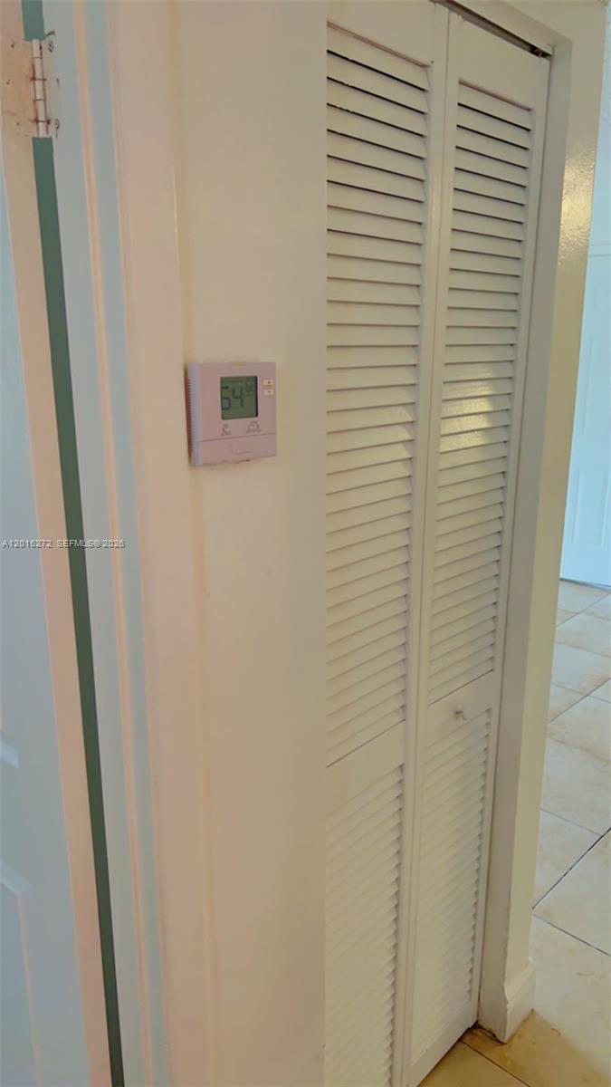 A white thermostat is mounted on a wall next to a louvered closet door — 1263 SW 46th Ave # 2104, Pompano Beach FL 33069, POMPANO BEACH, FL
