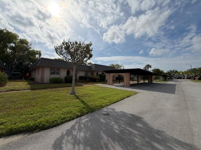 A single-story building with a covered carport stands beside a grassy lawn under a sky — 4412 SUNSTATE DRIVE UNIT A, NEW PORT RICHEY, FL