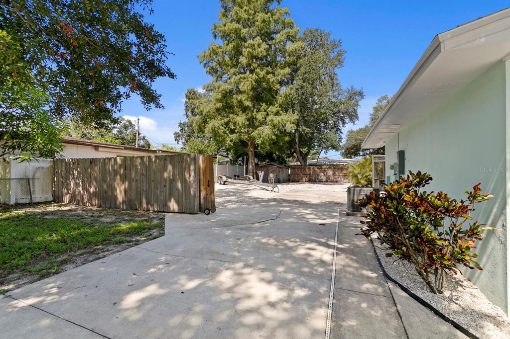 A swimming pool enclosed by a screened lanai sits in a backyard with a wooden fence — 2168 VICTORIA DRIVE, CLEARWATER, FL