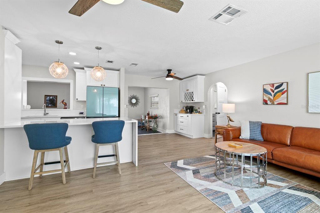 A gravel backyard features a boat trailer, a large tree, and a white vinyl fence — 2168 VICTORIA DRIVE, CLEARWATER, FL