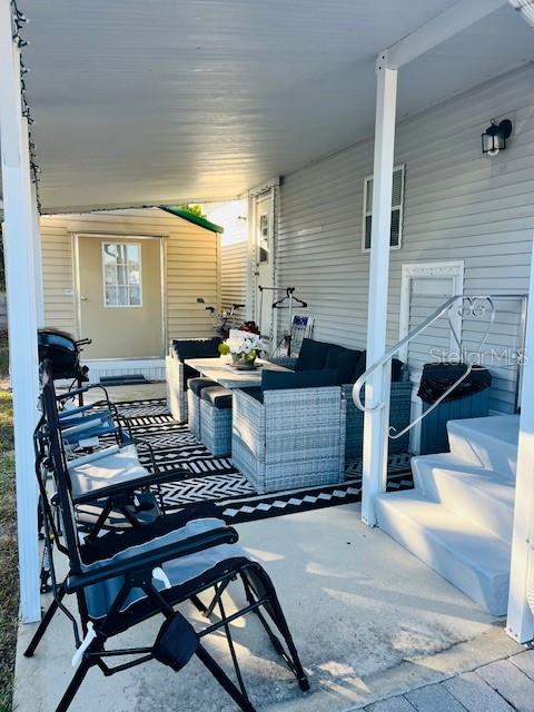 A covered patio features outdoor wicker furniture, a patterned rug, and steps leading to a home — 2429 LIMEWOOD AVENUE, CLERMONT, FL