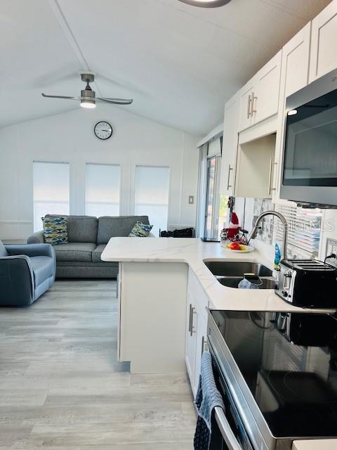 A modern kitchen with white cabinets and a breakfast bar overlooks a living room area — 2429 LIMEWOOD AVENUE, CLERMONT, FL