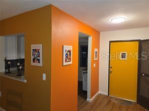 An interior view shows a bright orange wall, a yellow front door, and wood flooring — 4416 SPICEWOOD DRIVE UNIT J, BRADENTON, FL