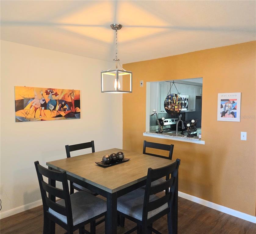 A dining area features a square wooden table, black chairs, and a modern pendant light — 4416 SPICEWOOD DRIVE UNIT J, BRADENTON, FL