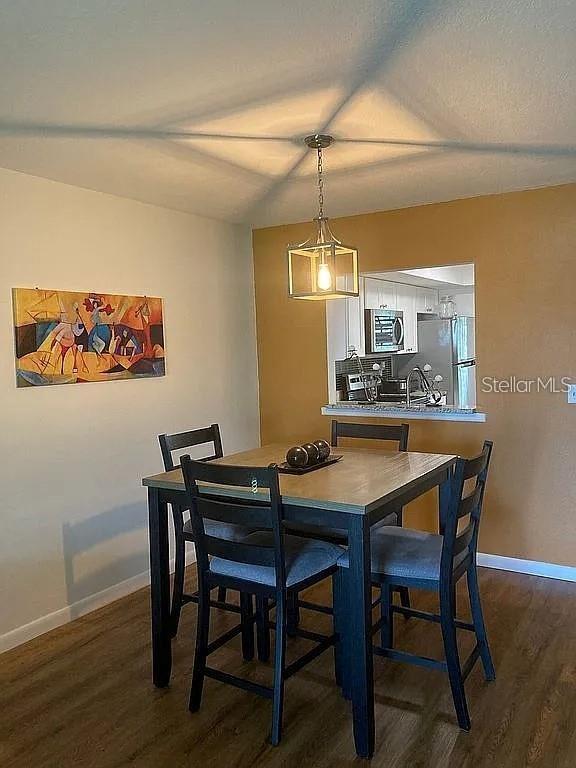 A dining area features a square table with four chairs under a modern pendant light — 4416 SPICEWOOD DRIVE UNIT J, BRADENTON, FL