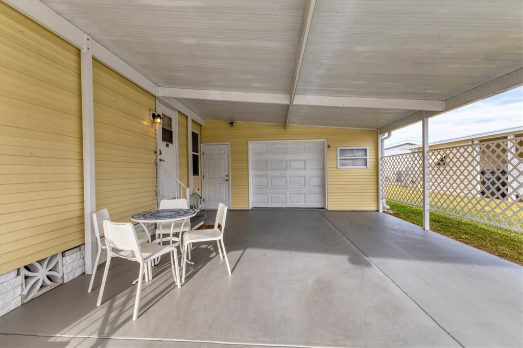 A covered concrete patio features a small table with chairs and yellow siding — 4532 12TH STREET COURT E, ELLENTON, FL