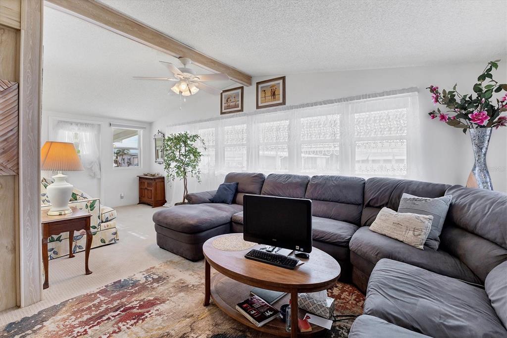 A living room features a gray sectional sofa, a wooden coffee table, and large windows — 4532 12TH STREET COURT E, ELLENTON, FL