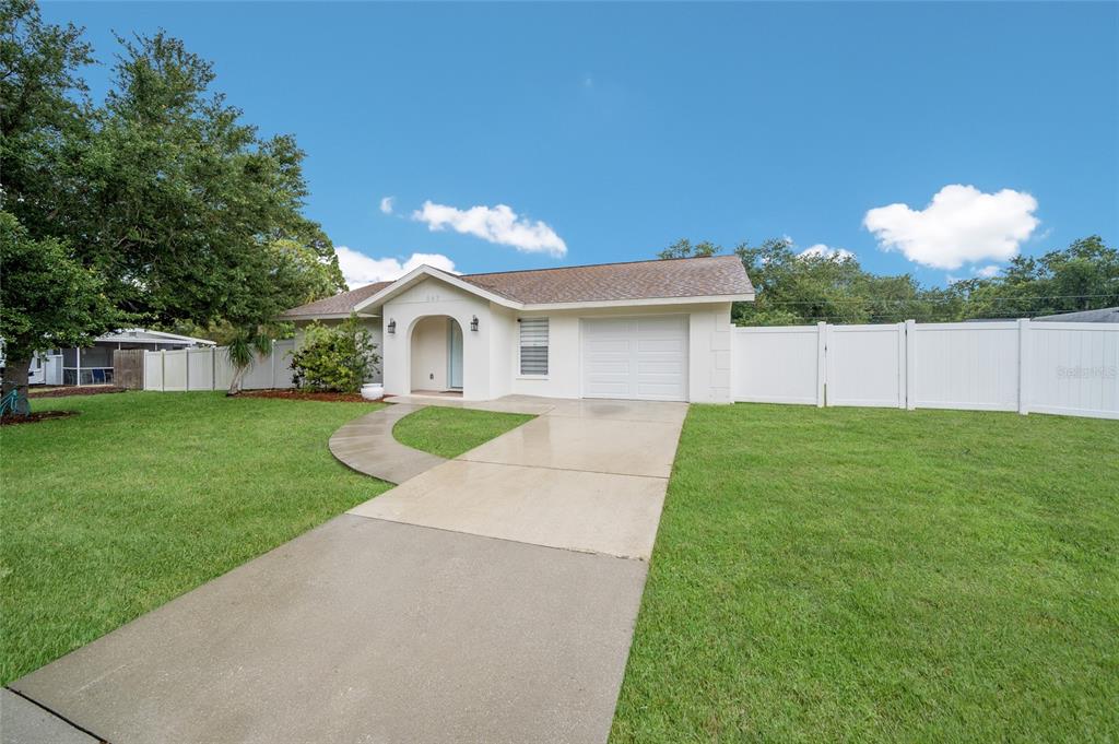A single-story house with a white exterior, a garage, and a white vinyl privacy fence — 643 MOBILE ROAD, VENICE, FL