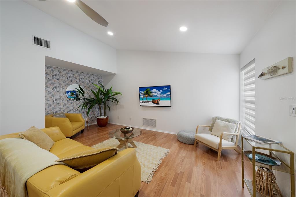 A living room features yellow leather seating, a patterned accent wall, and wood flooring — 643 MOBILE ROAD, VENICE, FL