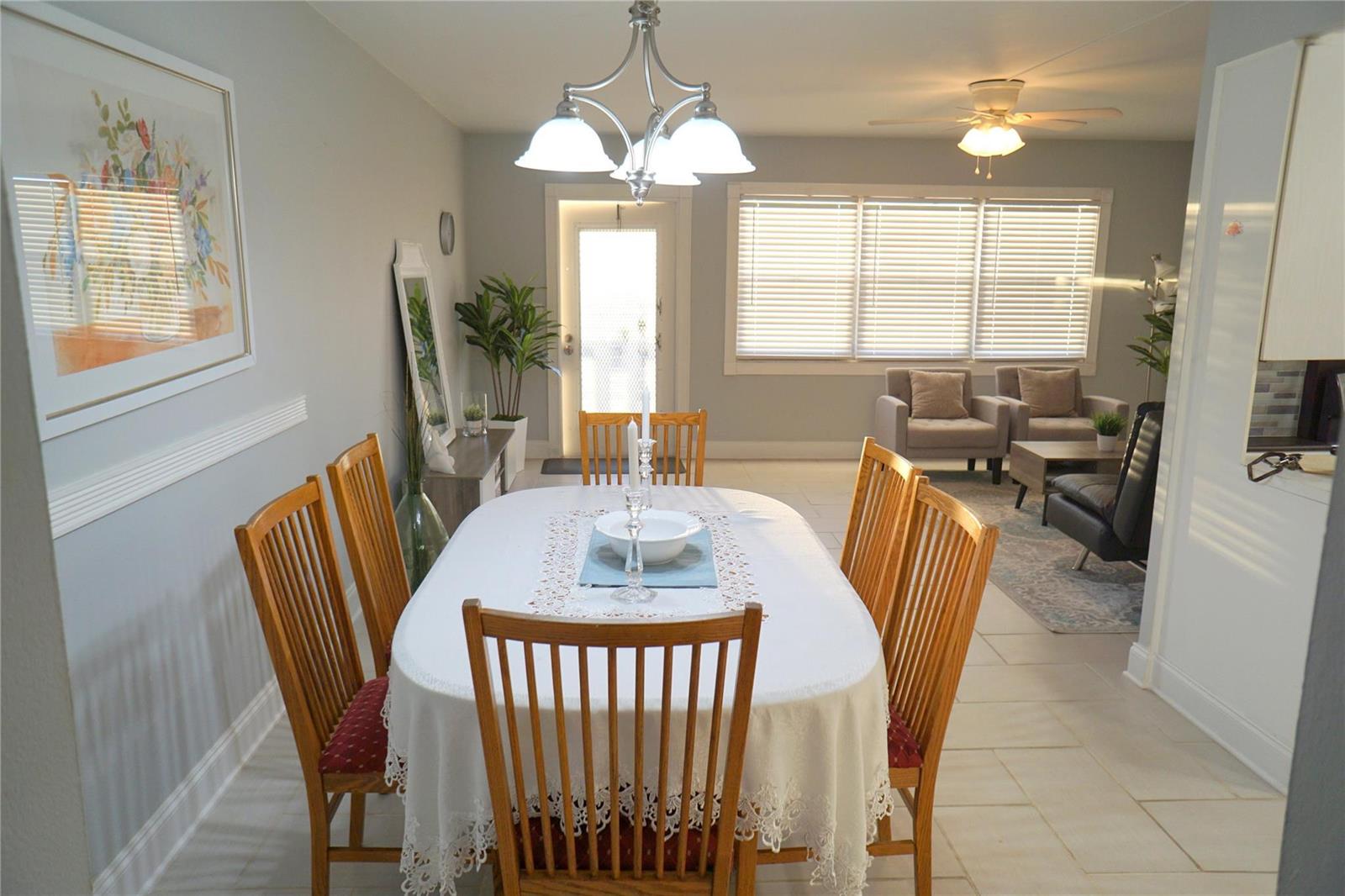 A dining room with a wooden table, chairs, and a chandelier, leading into a living area — 4029 Newport # 4029, Deerfield Beach FL 33442, DEERFIELD BEACH, FL
