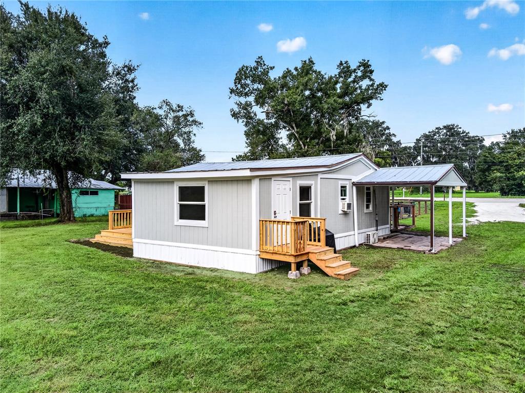 A light gray mobile home features a wooden deck, a covered patio, and a metal roof — 2727 SW HIGHWAY 17, ARCADIA, FL