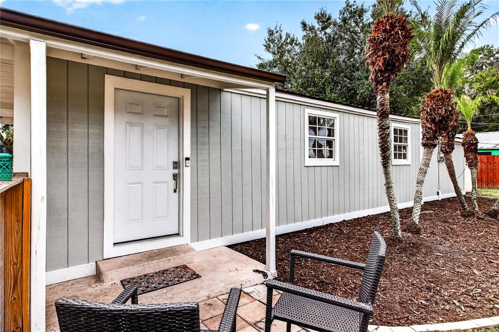 The exterior of a light gray house features a white door, two windows, and palm trees — 2727 SW HIGHWAY 17, ARCADIA, FL