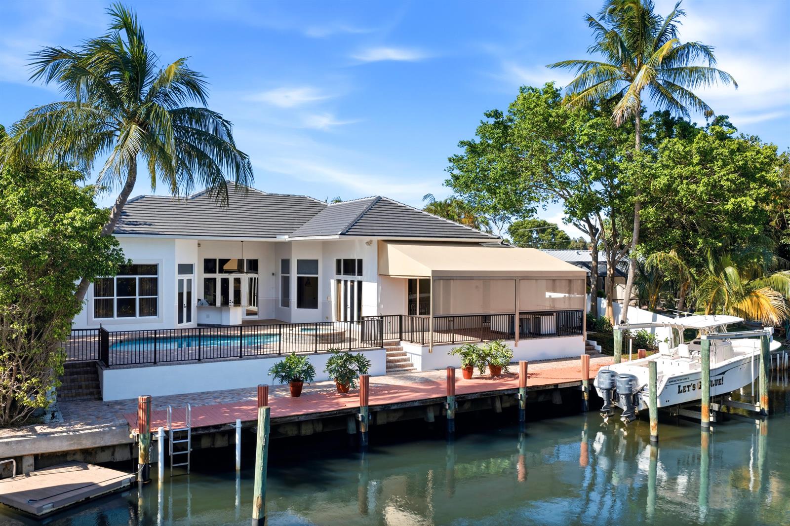 A waterfront house with a swimming pool, a covered patio, and a boat docked nearby — 608 Inlet Road, North Palm Beach FL 33408, NORTH PALM BEACH, FL
