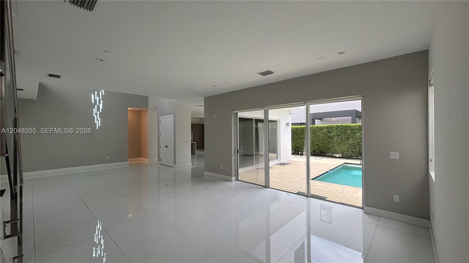 A spacious living room with white tile floors features a sliding glass door to a pool — 10108 NW 77th St # 10108, Doral FL 33178, DORAL, FL