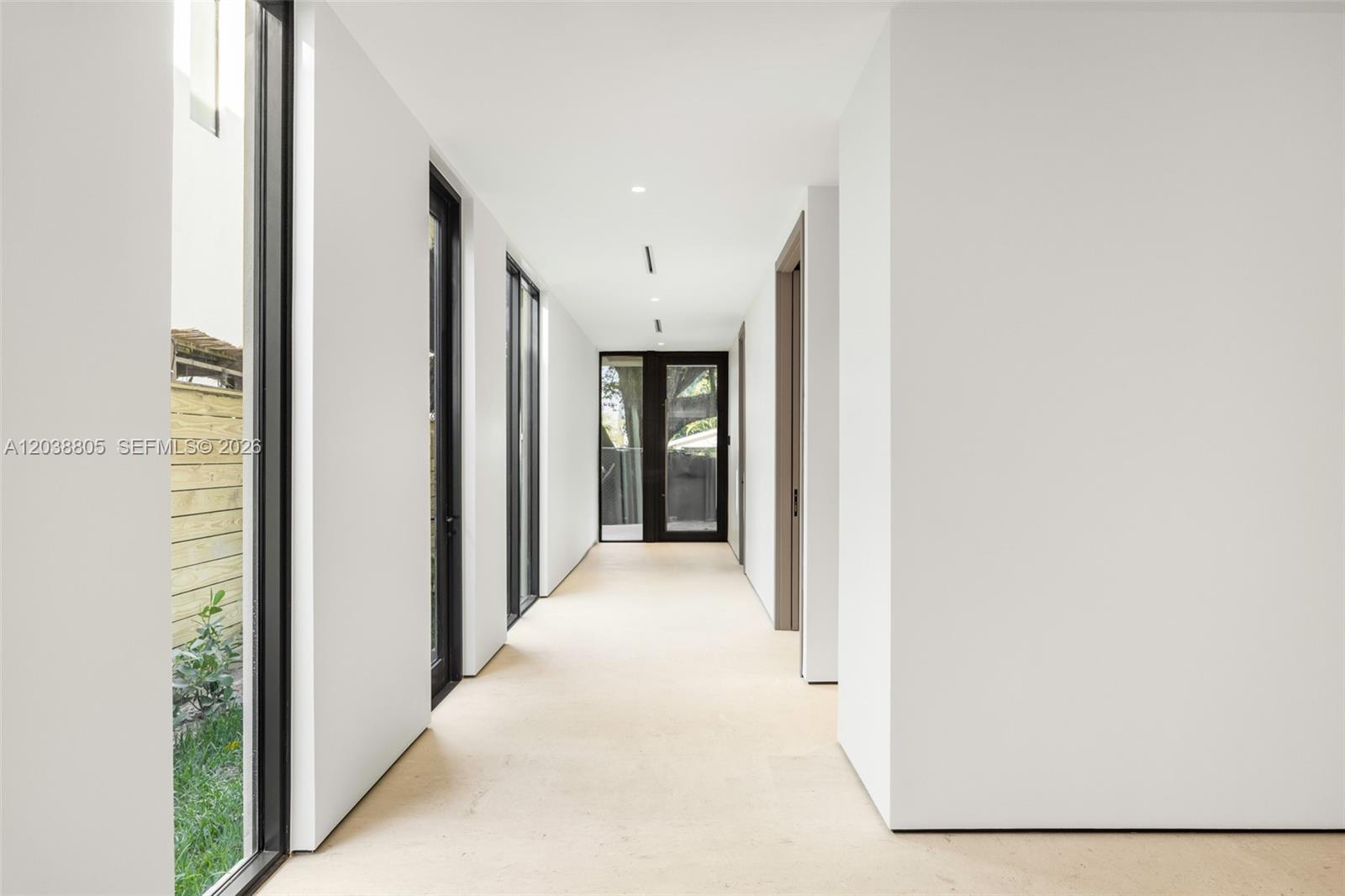 A minimalist hallway features white walls, light flooring, and glass doors leading outside — 3144 Elizabeth St, Coconut Grove FL 33133, COCONUT GROVE, FL