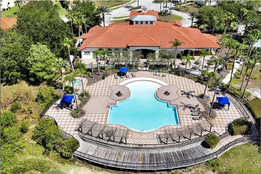 An aerial view shows a community clubhouse with a large swimming pool and wooden deck — 502 VIOLA DRIVE, DAVENPORT, FL