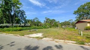 A vacant, grassy residential lot sits next to a house under a clear blue sky — 0 SE 45 street, Gainesville FL 32641, GAINESVILLE, FL
