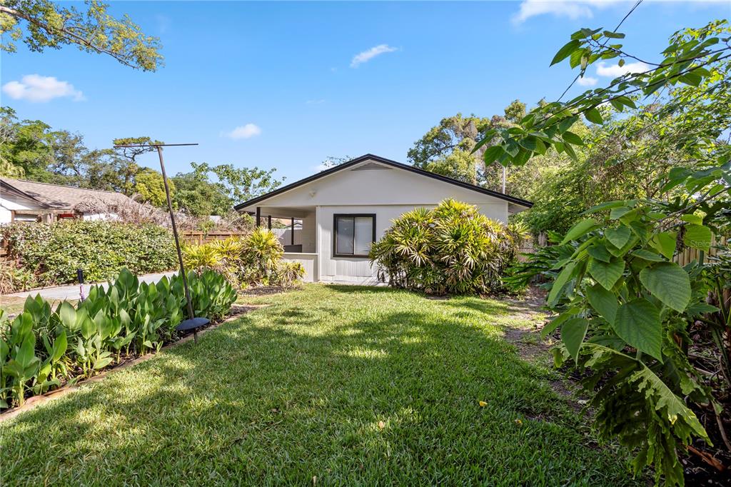 A backyard view of a single-story house with a lawn and surrounding landscaping — 847 CARLSON DRIVE, ORLANDO, FL