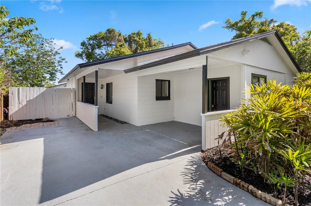 A white house exterior features a concrete driveway, a covered carport, and a wooden fence — 847 CARLSON DRIVE, ORLANDO, FL