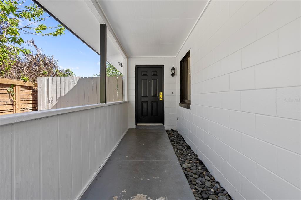 A covered entryway features a black front door, white block walls, and a pebble border — 847 CARLSON DRIVE, ORLANDO, FL