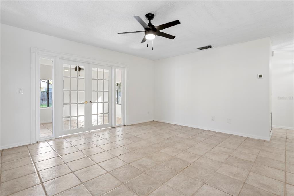 A bright room with white walls, beige tile flooring, a ceiling fan, and French doors — 847 CARLSON DRIVE, ORLANDO, FL
