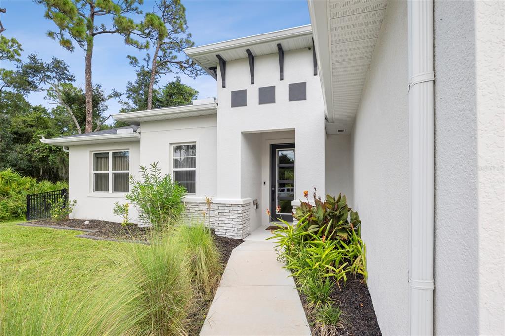A white stucco house exterior features a front entrance, stone accents, and a walkway — 4916 HADER ROAD, NORTH PORT, FL