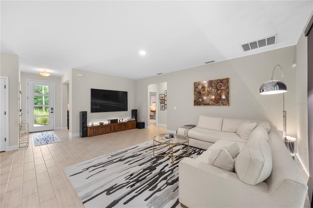 A living room features a large sectional sofa, a wall-mounted television, and a patterned rug — 4916 HADER ROAD, NORTH PORT, FL