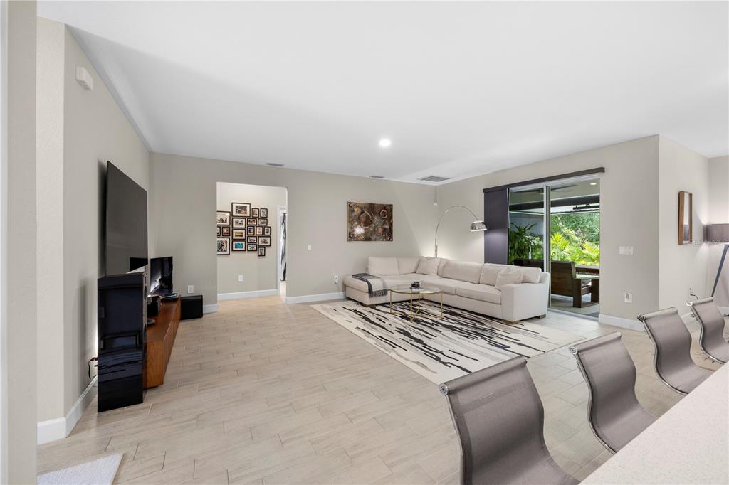 A spacious living room features light tile flooring, a beige sectional sofa, and sliding glass doors — 4916 HADER ROAD, NORTH PORT, FL