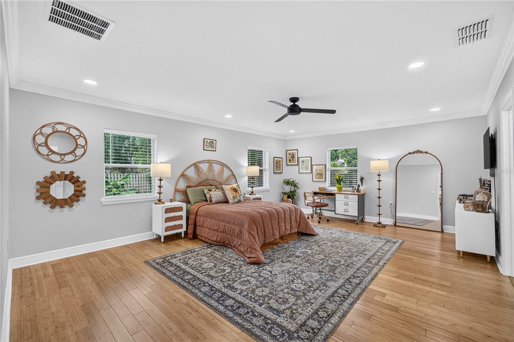 A bedroom with light wood floors, a rattan headboard, a large area rug, and wall decor — 2028 ILLINOIS STREET, ORLANDO, FL