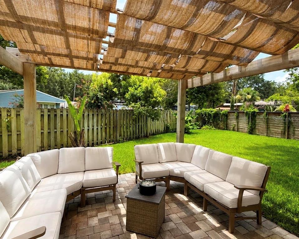 A patio features a wooden pergola with a fabric shade, modular seating, and a fire pit — 2028 ILLINOIS STREET, ORLANDO, FL