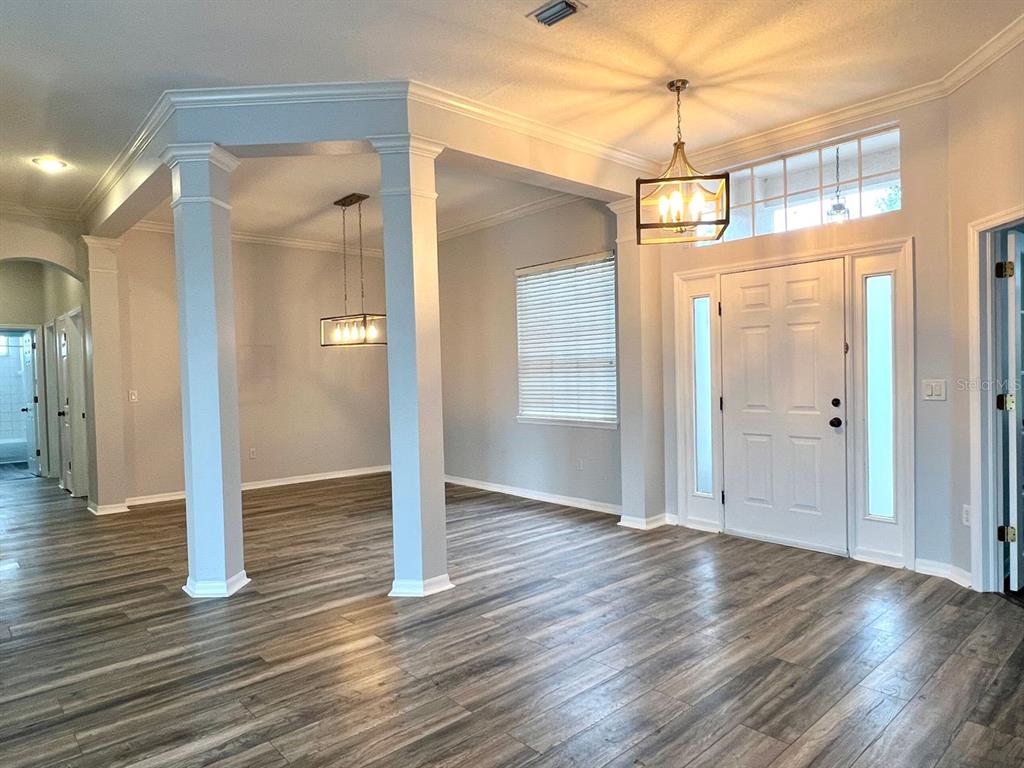 An entryway with wood-look flooring, white columns, and two hanging light fixtures — 18111 SUGAR BROOKE DRIVE, TAMPA, FL