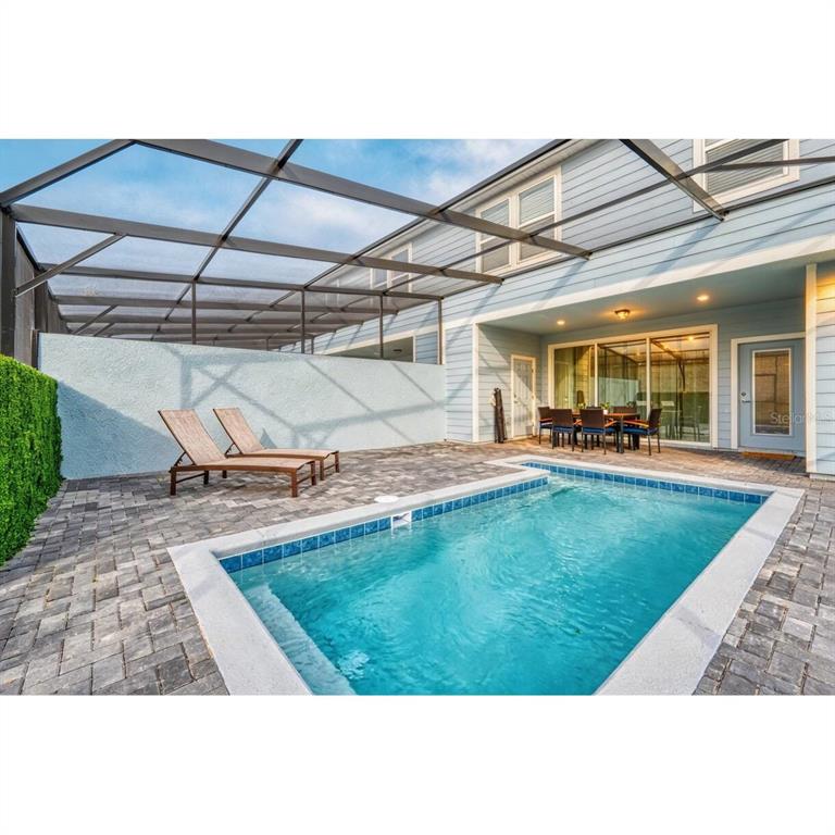 A screened-in patio features a rectangular swimming pool, lounge chairs, and a dining set — 806 PARADISE DRIVE, DAVENPORT, FL