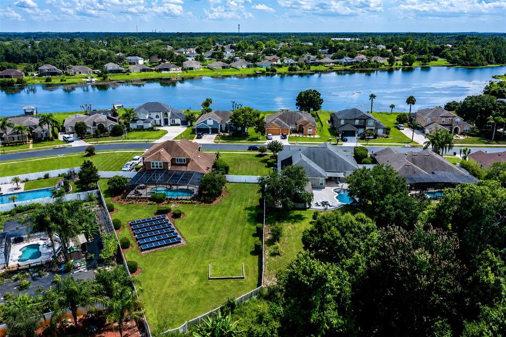 An aerial view shows suburban houses with swimming pools and solar panels near a lake — 407 OSPREY LAKES CIRCLE, OVIEDO, FL