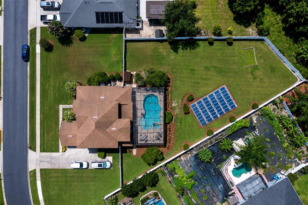 An aerial view shows a house with a pool enclosure and ground-mounted solar panels — 407 OSPREY LAKES CIRCLE, OVIEDO, FL