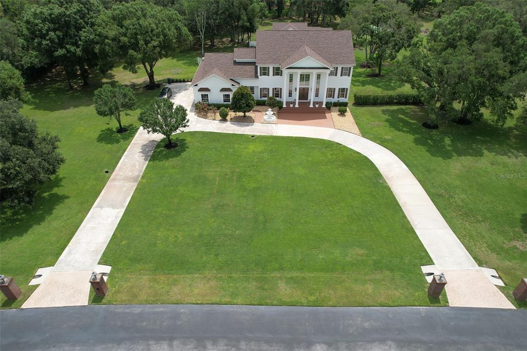 An aerial view shows a large house with a swimming pool surrounded by wooded acreage — 11444 HAMMOCK OAKS CT, LITHIA, FL