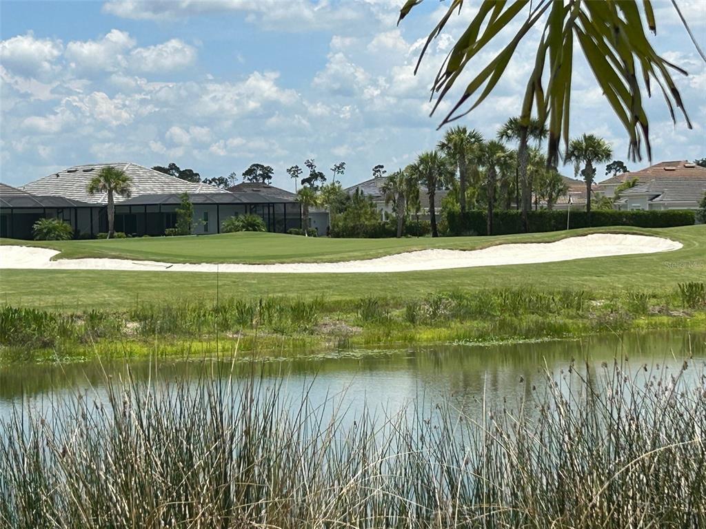 A view of a golf course green with sand bunkers and a pond in front — 15983 GRASSLAND LANE UNIT 3411, PUNTA GORDA, FL